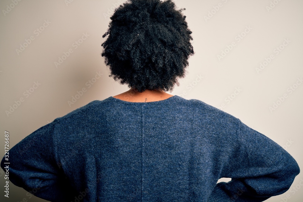 Young beautiful African American afro woman with curly hair wearing casual sweater standing backwards looking away with arms on body Young beautiful African American afro woman with curly hair wearing casual sweater standing backwards looking away with arms on body
