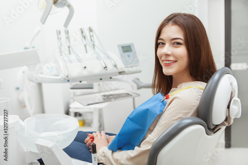 Happy beautiful woman with healthy white teeth sitting in dental chair at the clinic  copy space