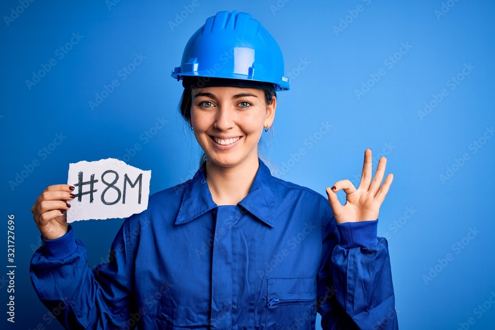Beautiful worker woman wearing hardhat and uniform celebrating 8th march womens day doing ok sign with fingers, excellent symbol Beautiful worker woman wearing hardhat and uniform celebrating 8th march womens day doing ok sign with fingers, excellent symbol