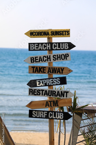Direction signpost on sea background. Wooden pointer to the beach  Surf club  Shop  ATM.
