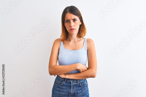 Beautiful redhead woman standing over isolated background skeptic and nervous, disapproving expression on face with crossed arms. Negative person.