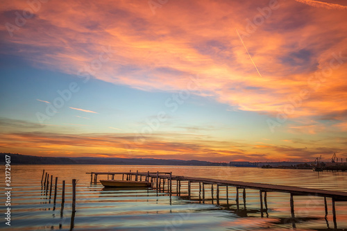 Magnificent sunset at the seashore with wooden pier and boat.