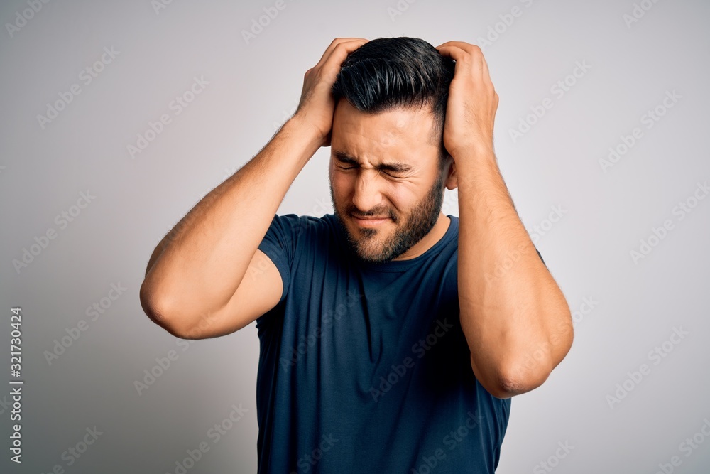 Young handsome man wearing casual t-shirt standing over isolated white background suffering from headache desperate and stressed because pain and migraine. Hands on head. Young handsome man wearing casual t-shirt standing over isolated white background suffering from headache desperate and stressed because pain and migraine. Hands on head.