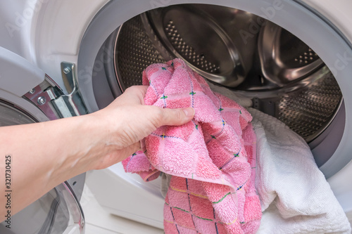 Woman housewife pull the laundry out of or load a washing machine