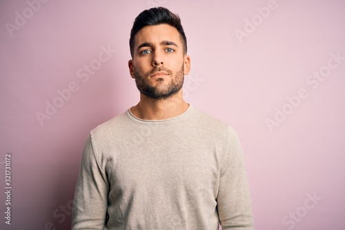 Young handsome man wearing casual sweater standing over isolated pink background Relaxed with serious expression on face. Simple and natural looking at the camera. © Krakenimages.com