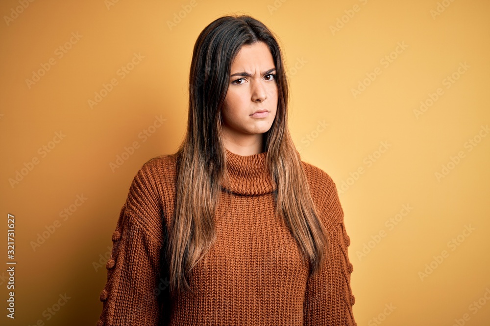 Young beautiful girl wearing casual sweater standing over isolated yellow background skeptic and nervous, frowning upset because of problem. Negative person. Young beautiful girl wearing casual sweater standing over isolated yellow background skeptic and nervous, frowning upset because of problem. Negative person.