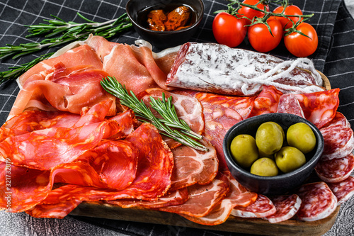 Spanish cold meat assortment. Chorizo, fuet, LOMO, jamon Iberico, olives. Gray background. Top view