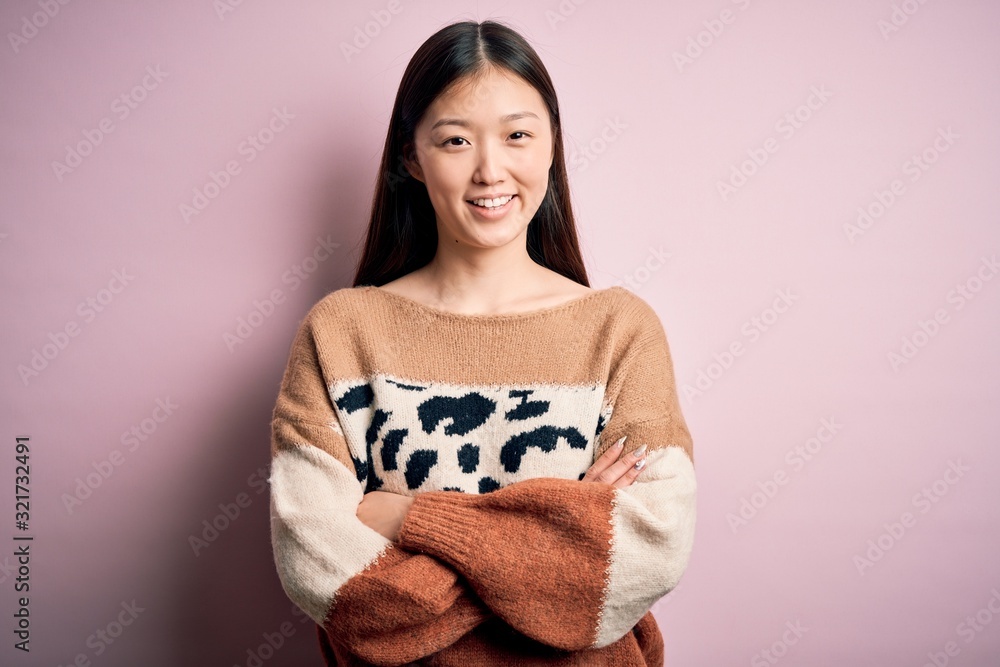 Young beautiful asian woman wearing animal print fashion sweater over pink isolated background happy face smiling with crossed arms looking at the camera. Positive person. Young beautiful asian woman wearing animal print fashion sweater over pink isolated background happy face smiling with crossed arms looking at the camera. Positive person.