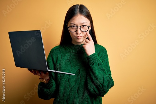 Young asian business woman wearing glasses and working using computer laptop Pointing to the eye watching you gesture, suspicious expression