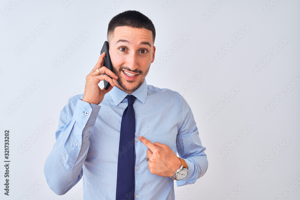Young handsome business man calling using smartphone over isolated background with surprise face pointing finger to himself Young handsome business man calling using smartphone over isolated background with surprise face pointing finger to himself