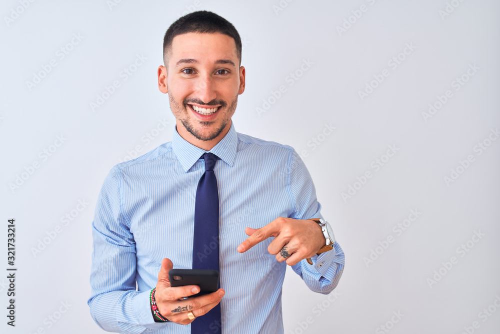 Young handsome business man using smartphone over isolated background very happy pointing with hand and finger Young handsome business man using smartphone over isolated background very happy pointing with hand and finger