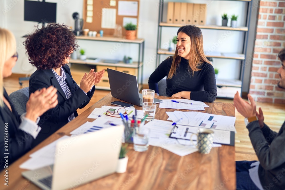 Group of business workers smiling happy and confident. Working together with smile on face applauding one of them at the office Group of business workers smiling happy and confident. Working together with smile on face applauding one of them at the office