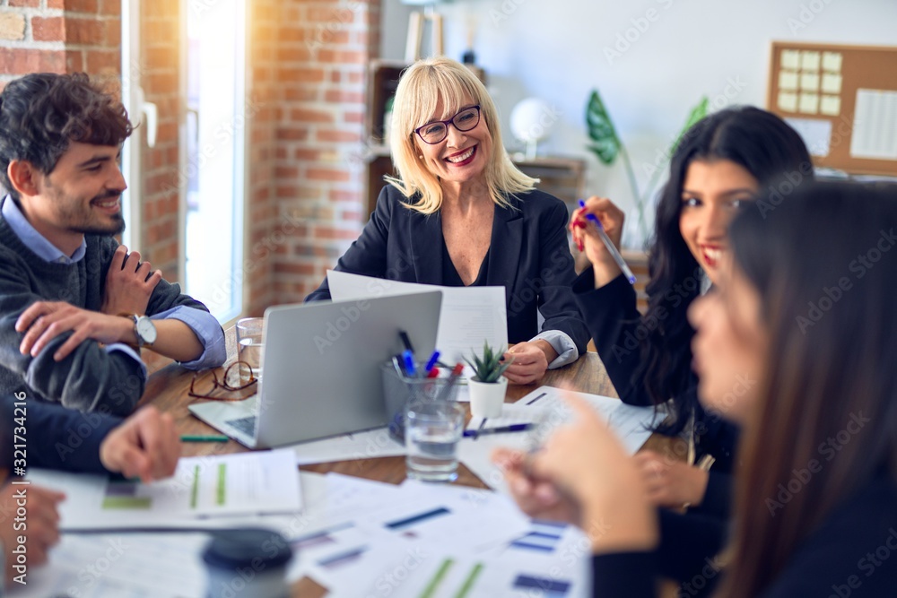 Group of business workers smiling happy and confident. Working together with smile on face using laptop and speaking at the office Group of business workers smiling happy and confident. Working together with smile on face using laptop and speaking at the office