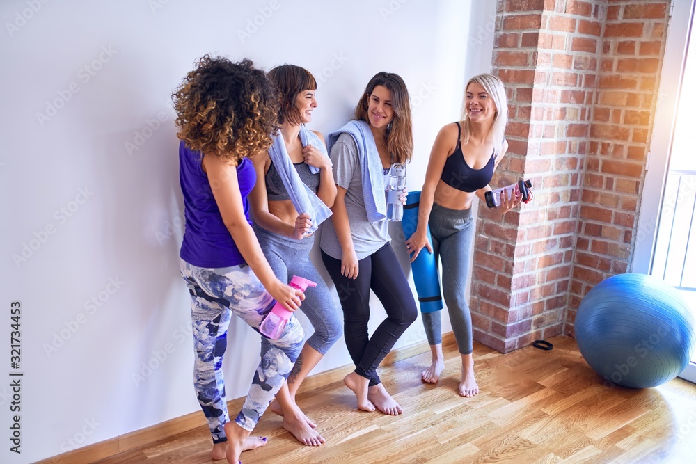 Fototapeta premium Young beautiful group of sportswomen smiling happy. Standing speaking with smile on face after class of yoga at gym