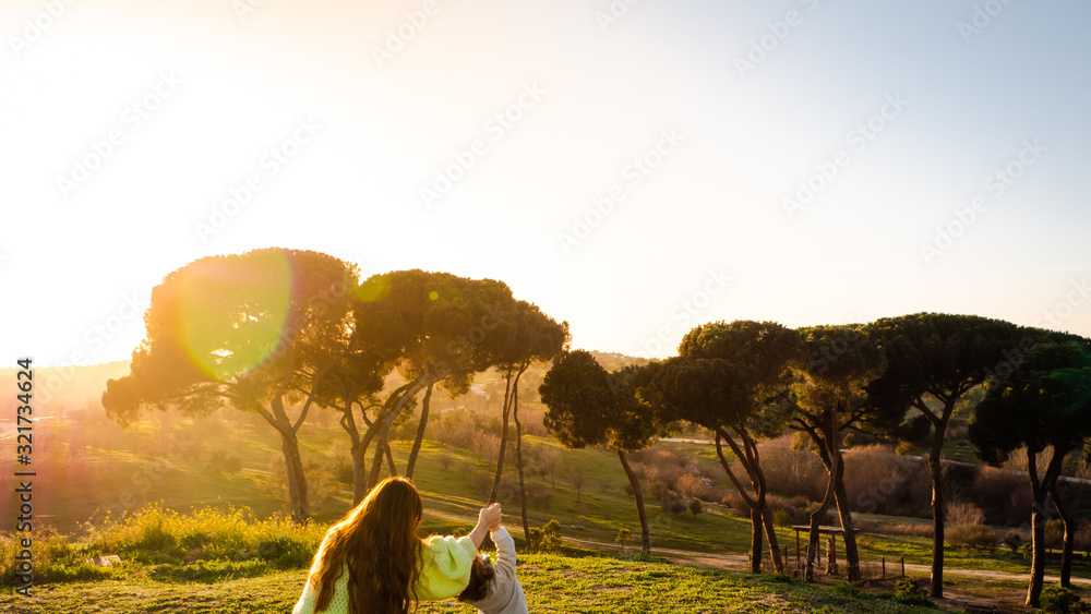Naklejka premium A pregnant woman is playing with her little son in a park at sunset in Madrid, Spain