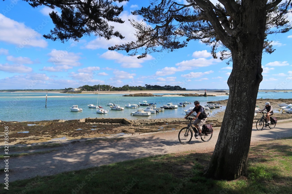 Fototapeta premium Deux cyclistes pratiquant le cyclotourisme sur une piste cyclable au bord de la mer, au Croisic en Loire-Atlantique (France)