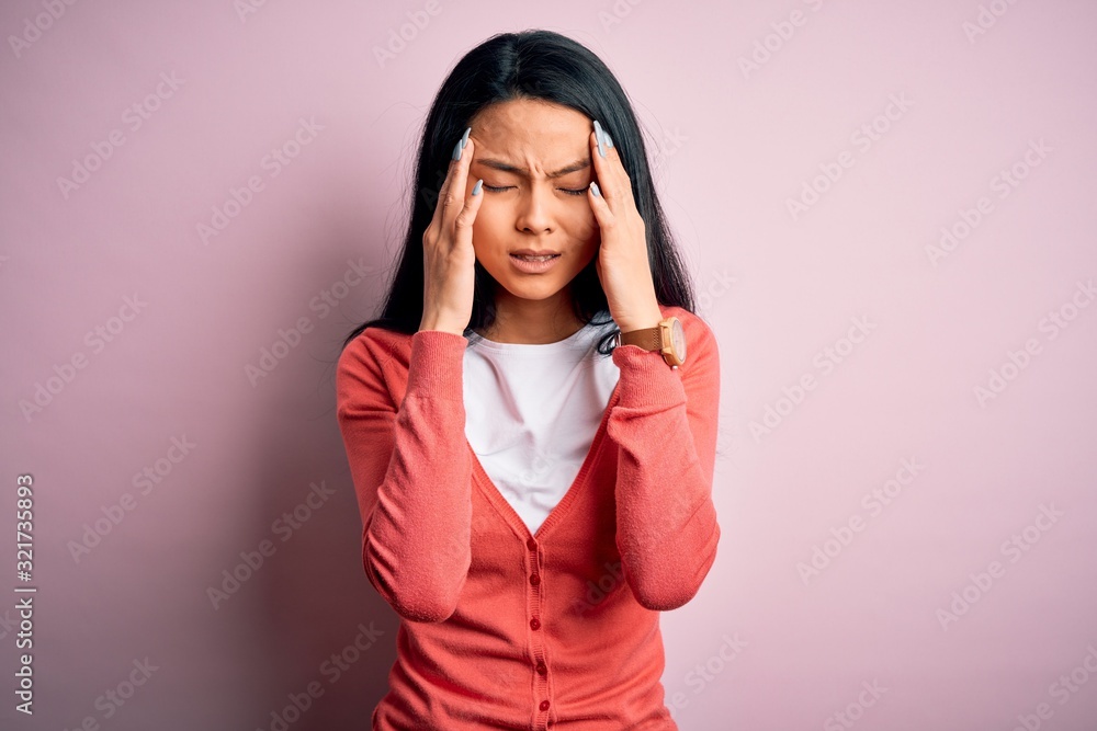 Young beautiful chinese woman wearing casual sweater over isolated pink background with hand on headache because stress. Suffering migraine. Young beautiful chinese woman wearing casual sweater over isolated pink background with hand on headache because stress. Suffering migraine.