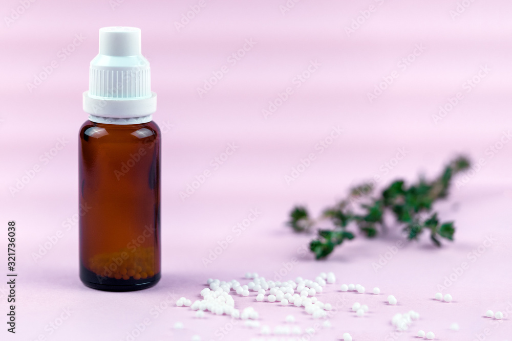 Homeopathic balls and glass bottle on a pink background. Alternative homeopathy herbal medicine, healthcare concept and pills. copyspace for text