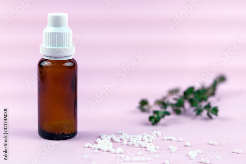 Homeopathic balls and glass bottle on a pink background. Alternative homeopathy herbal medicine  healthcare concept and pills. copyspace for text