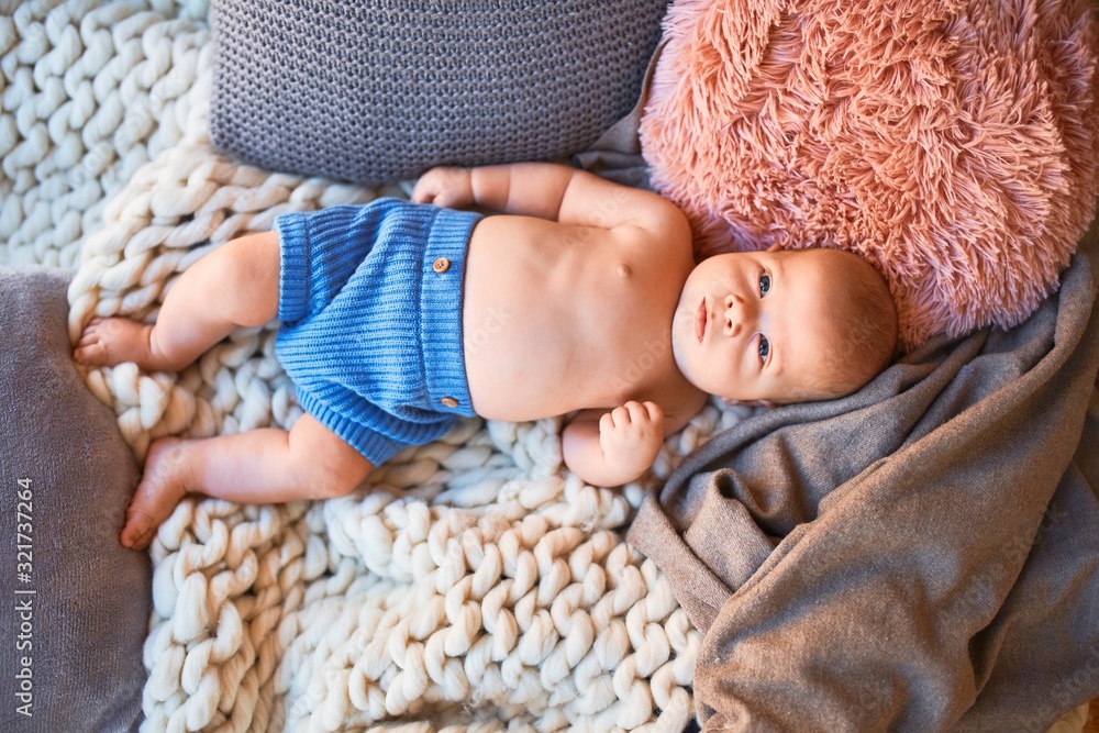 Adorable baby lying down on the sofa over blanket at home. Newborn relaxing and resting comfortable - obrazy, fototapety, plakaty 