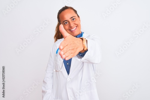 Middle age mature doctor woman wearing stethoscope over isolated background smiling friendly offering handshake as greeting and welcoming. Successful business.