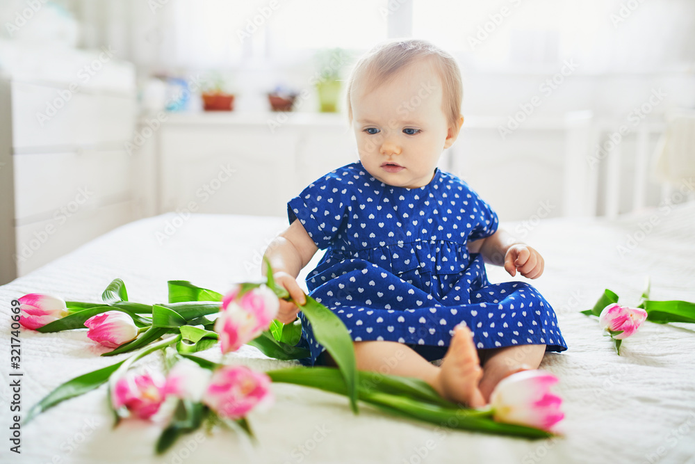 Baby girl in blue dress playing with bunch of pink tulips Baby girl in blue dress playing with bunch of pink tulips