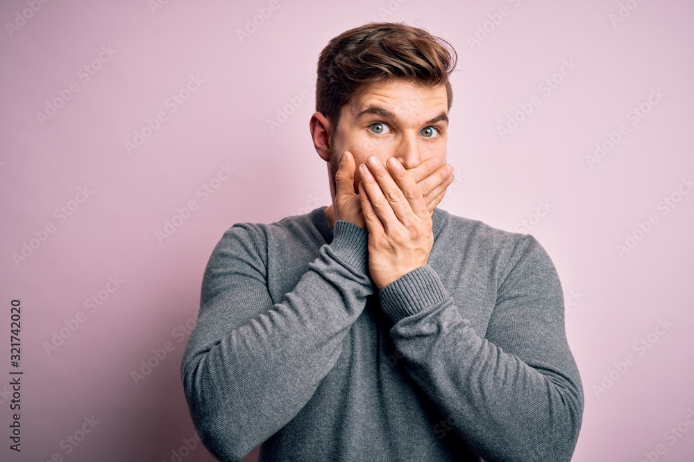 Young handsome blond man with beard and blue eyes wearing casual sweater shocked covering mouth with hands for mistake. Secret concept. Young handsome blond man with beard and blue eyes wearing casual sweater shocked covering mouth with hands for mistake. Secret concept.