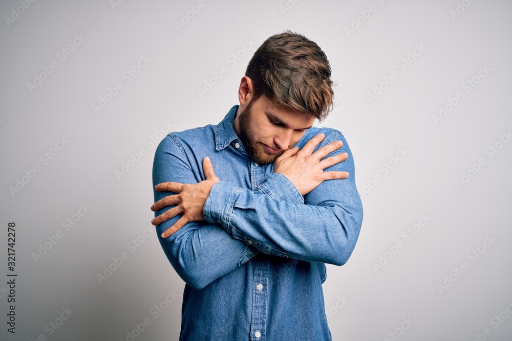 Young handsome blond man with beard and blue eyes wearing casual denim shirt Hugging oneself happy and positive, smiling confident. Self love and self care Young handsome blond man with beard and blue eyes wearing casual denim shirt Hugging oneself happy and positive, smiling confident. Self love and self care
