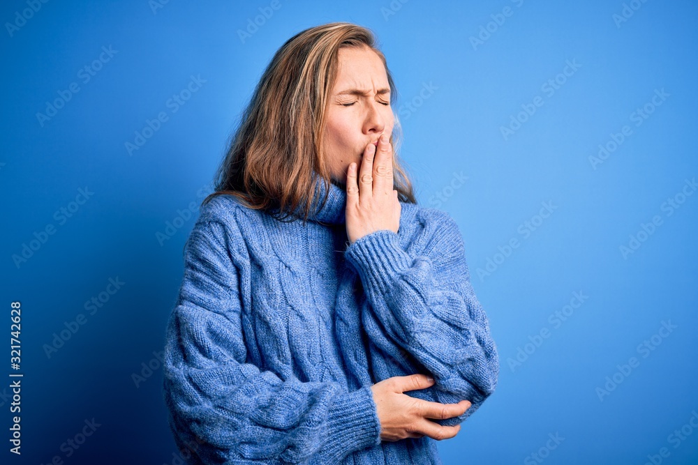 Young beautiful blonde woman wearing casual turtleneck sweater over blue background bored yawning tired covering mouth with hand. Restless and sleepiness. Young beautiful blonde woman wearing casual turtleneck sweater over blue background bored yawning tired covering mouth with hand. Restless and sleepiness.