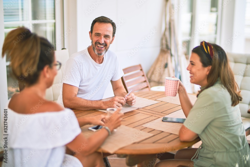 Beautiful family sitting on terrace drinking cup of coffee speaking and smiling Beautiful family sitting on terrace drinking cup of coffee speaking and smiling