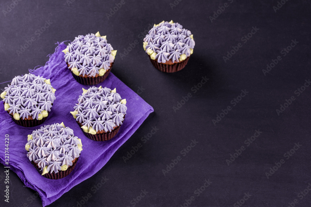 Delicate chocolate cupcakes close-up on a dark table with a napkin. Delicate chocolate cupcakes close-up on a dark table with a napkin.
