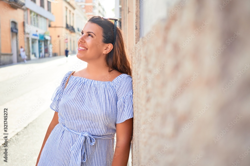 Young beautiful woman smiling happy leaning on the wall of city streets on a sunny day of summer Young beautiful woman smiling happy leaning on the wall of city streets on a sunny day of summer