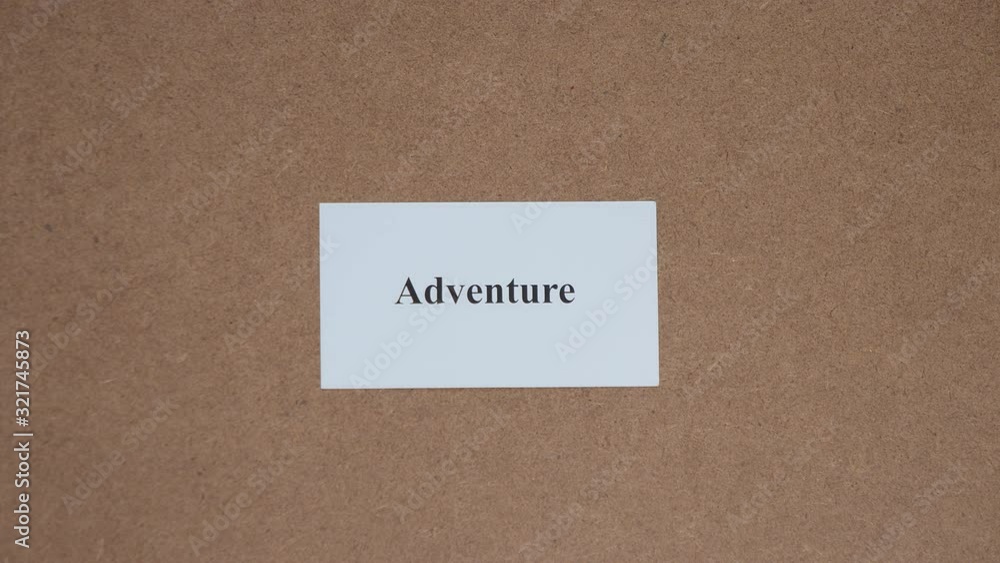 ADVENTURE. Top shot - Hand puts paper card with word. CORE VALUE concept. ADVENTURE. Top shot - Hand puts paper card with word. CORE VALUE concept.