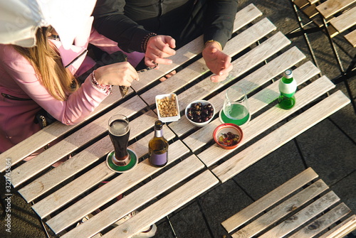 Casal de namorados sentados numa mesa numa esplanada a comer e beber produtos tipicos portugueses: cerveja, amendoins, azeitonas, cerveja, cola