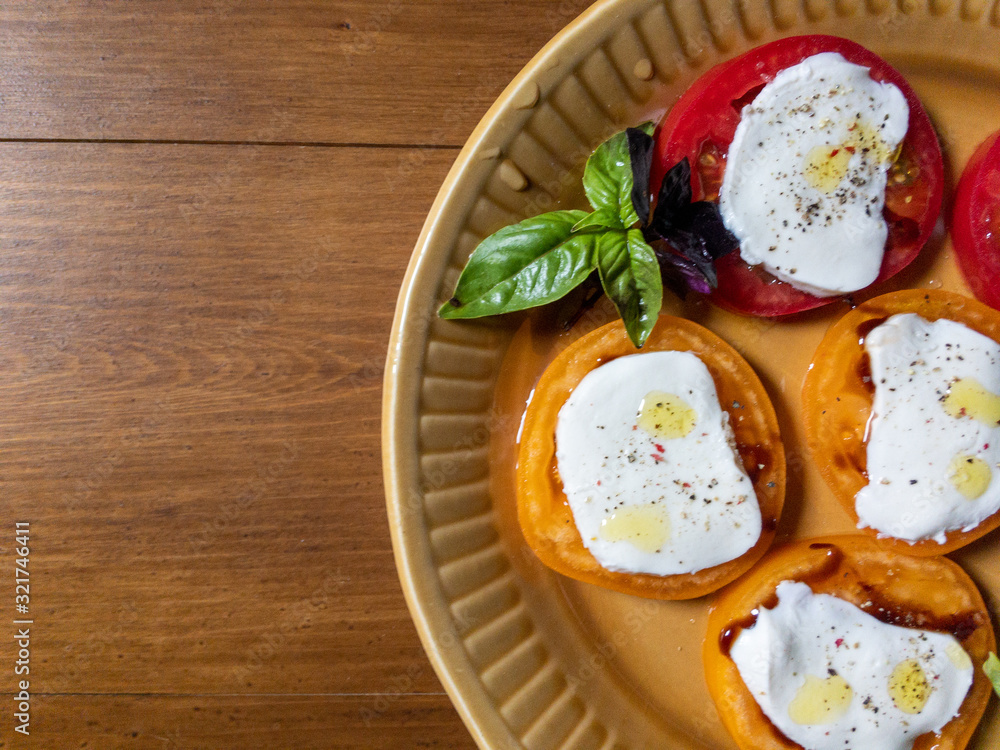 Sliced red and orange tomatoes with mozzarella, olive oil, basil
