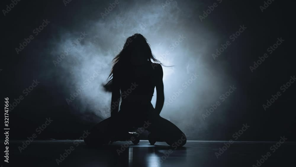 Silhouette of a sexy girl dancing sexy dance in high heels with light in her back. Black smoke background Silhouette of a sexy girl dancing sexy dance in high heels with light in her back. Black smoke background