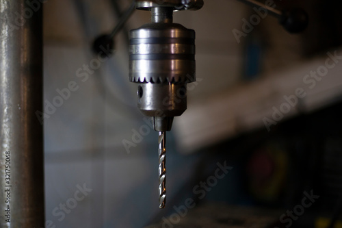 Drill for metal. Drilling machine is in the workshop. Handwork in the garage. An old cnc-free machine. Darkened room with tools. Men's work. making holes.