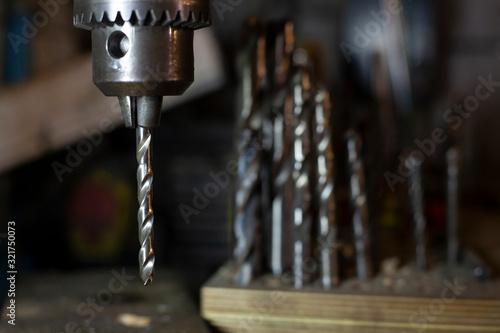 Drill for metal. Drilling machine is in the workshop. Handwork in the garage. An old cnc-free machine. Darkened room with tools. Men's work. making holes.