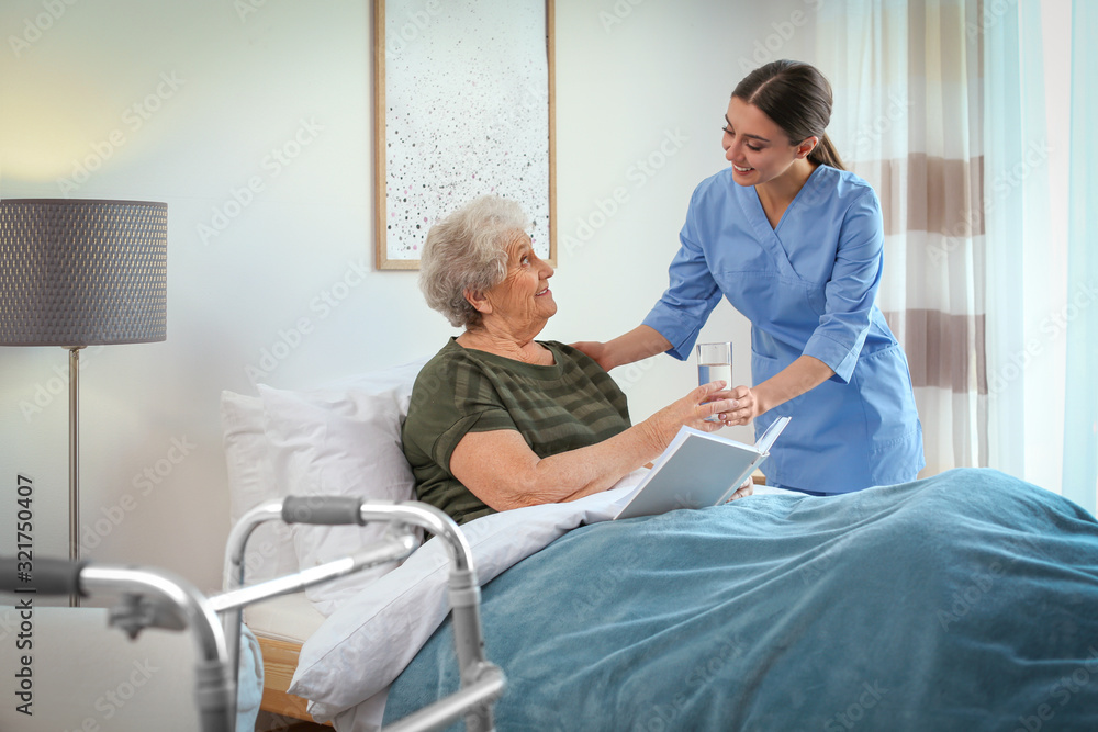Care worker giving water to elderly woman in geriatric hospice Care worker giving water to elderly woman in geriatric hospice