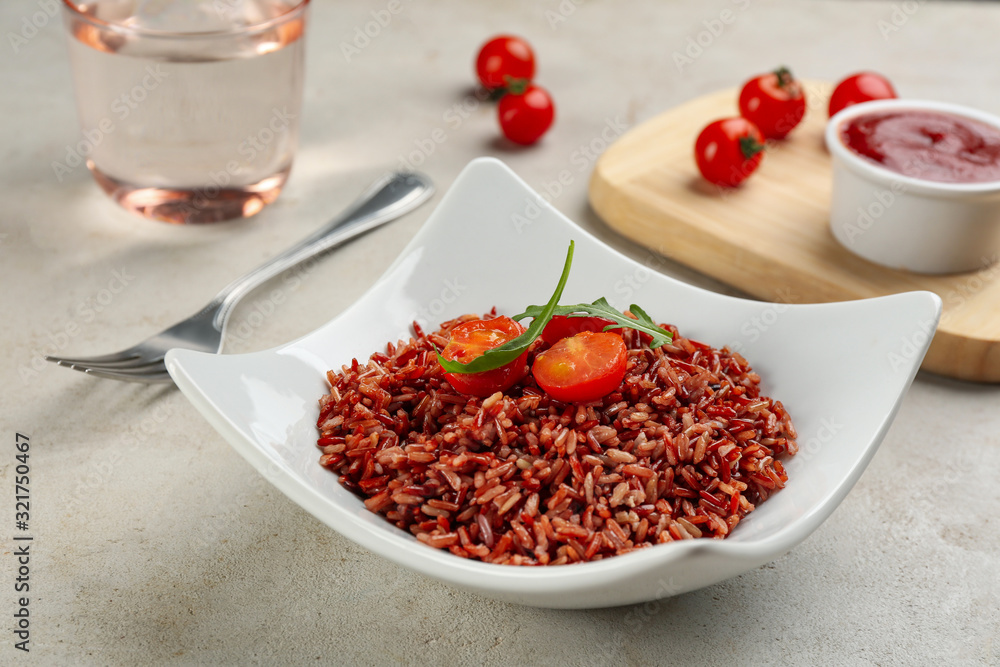 Tasty brown rice with tomatoes on light grey table Tasty brown rice with tomatoes on light grey table