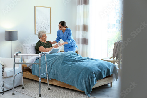 Valokuva Care worker giving water to elderly woman in geriatric hospice