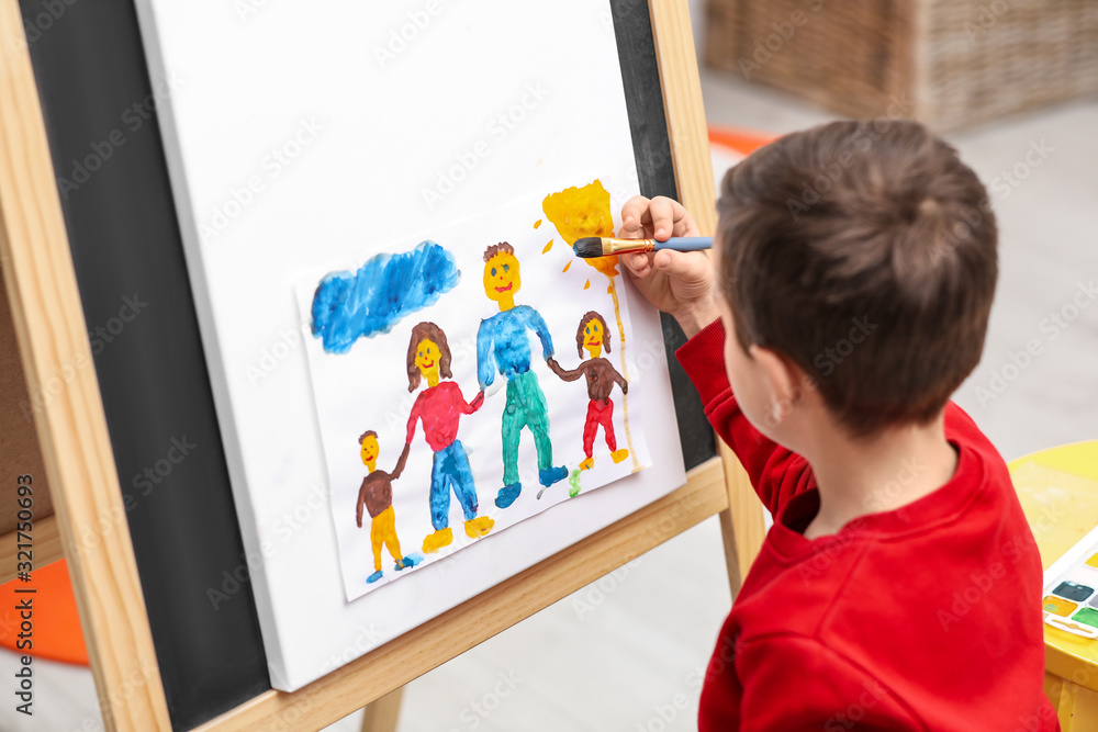 Little child painting on easel in room Little child painting on easel in room