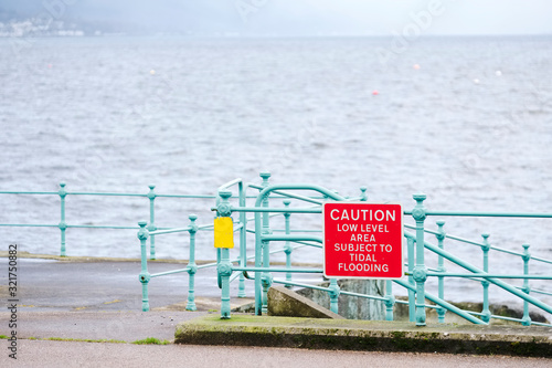 Принти на полотні Low tide area subject to tidal flooding warning sign at harbour wall