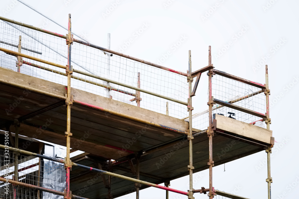 Scaffold platform and poles in blue sky at high level of construction building site Scaffold platform and poles in blue sky at high level of construction building site