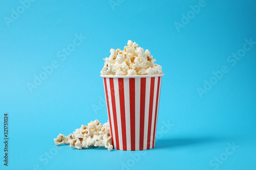 Delicious popcorn in paper cup on light blue background