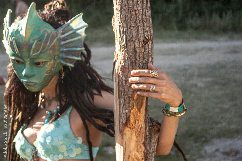 Obraz premium Beautiful tanned girl in the mask of an ancient goddess. The dancer shows movement. Mysterious girl beckons guys. A stranger is looking for a man. Beautiful body of a woman. Unusual high quality mask.
