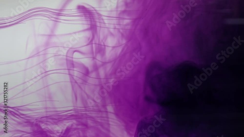 Colourful dynamic abstract background. Potassium permanganate crystals in the water. Close up. 4K resolution. photo