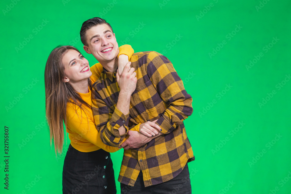 Portrait of a cheerful young couple standing isolated over green background, looking far away, smiling. Portrait of a cheerful young couple standing isolated over green background, looking far away, smiling.