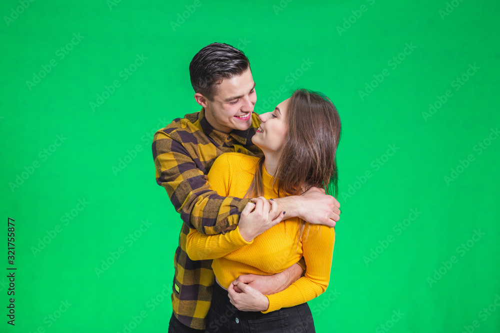 Lovely portrait of happy young couple in love embracing each other over green background. Lovely portrait of happy young couple in love embracing each other over green background.