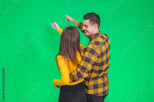 Amazed young people looking and pointing away at something really increadible on green background. photo